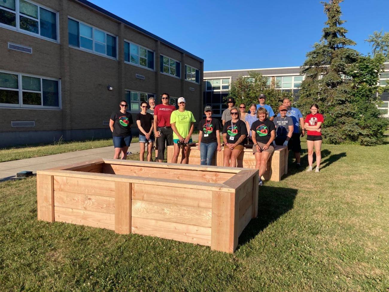 Members of the Mynderse Academy farm to school team and volunteers pose with newly built wooden garden beds outside at the school